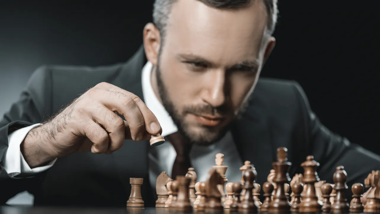Man planning his next move in a chess game, illustrating strategic vs. tactical planning