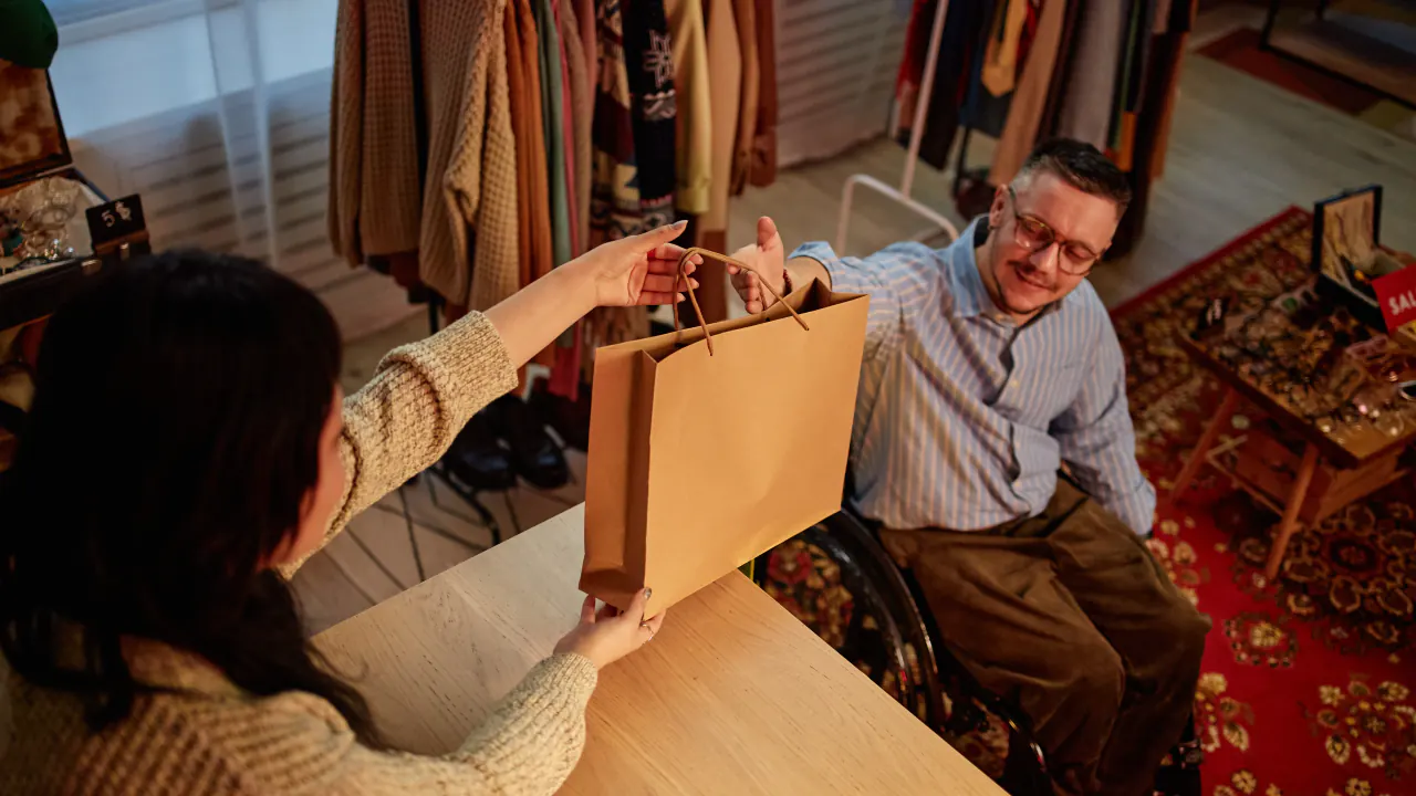 Store clerk handing a shopping bag to a customer, illustrating upselling