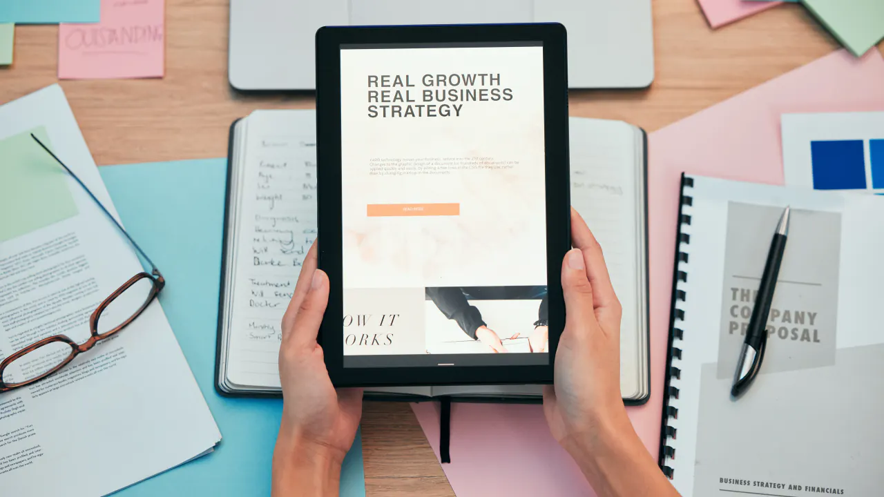 Hands holding a tablet reading Real Growth Real Business Strategy, illustrating what a lead magnet is