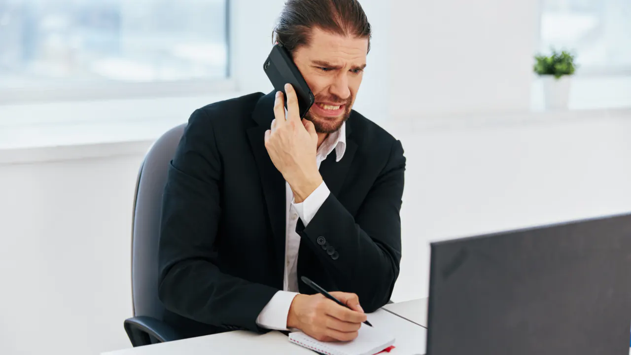 Businessman on a phone call taking notes, illustrating what cold calling is